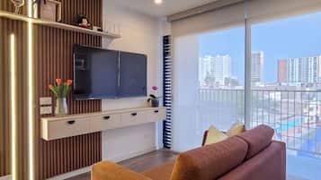 Ein modernes Wohnzimmer mit einer Couch, einem Fernseher und Blick auf die Stadt.