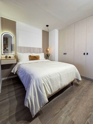 Ein modernes Schlafzimmer mit einem großen Bett, einem Nachttisch mit Spiegel und einem Kleiderschrank.
