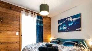 Ein Zimmer mit Holzwänden, einem Bett mit gestreifter Decke, einem Wellenbild und einer hängenden Leuchte.