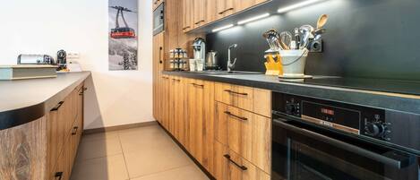 Una cocina moderna con armarios de madera, un horno Bosch y una máquina de café.