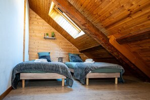 Una habitació amb dos llits de fusta, un fanal i un sostre de fusta.