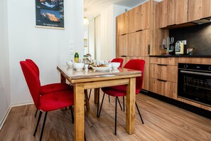 Eine moderne Küche mit Holzausstattung, einem Esstisch mit roten Stühlen und einem eingebauten Backofen.
