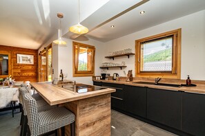 Une cuisine moderne avec un îlot central en bois, des tabourets de bar et une grande fenêtre.