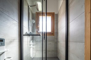 A modern shower with a glass door, a control panel, and a window above the shower. - Chalet Nanouk - exposé plein sud (La Salle-les-Alpes)