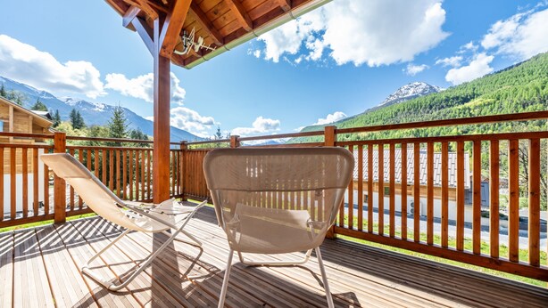 A wooden deck with a lounge chair and a wicker chair, overlooking a mountain landscape. - Chalet Nanouk - exposé plein sud (La Salle-les-Alpes)