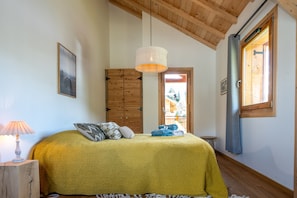 Un dormitorio con cama, armario de madera, lámpara colgante y puerta que da a un área exterior.