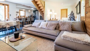 A modern living room with a sofa, coffee table, and a staircase leading to an upper level. - Chalet Nanouk - exposé plein sud (La Salle-les-Alpes)