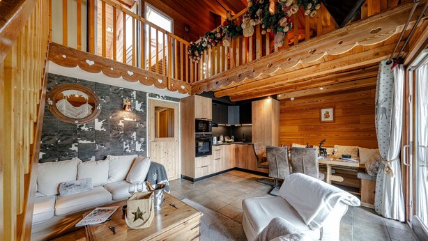 En inredning med träpaneler, en soffa, ett soffbord och ett köksområde.