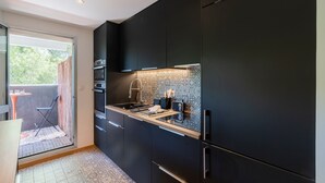Eine moderne Küche mit dunklen Schränken, einer gefliesten Spritzschutzwand und einem kleinen Essbereich mit Tisch und Stühlen.