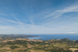 Ein weiter Panoramablick auf eine Küstenlandschaft mit sanften Hügeln, Feldern und einer fernen Küstenlinie.