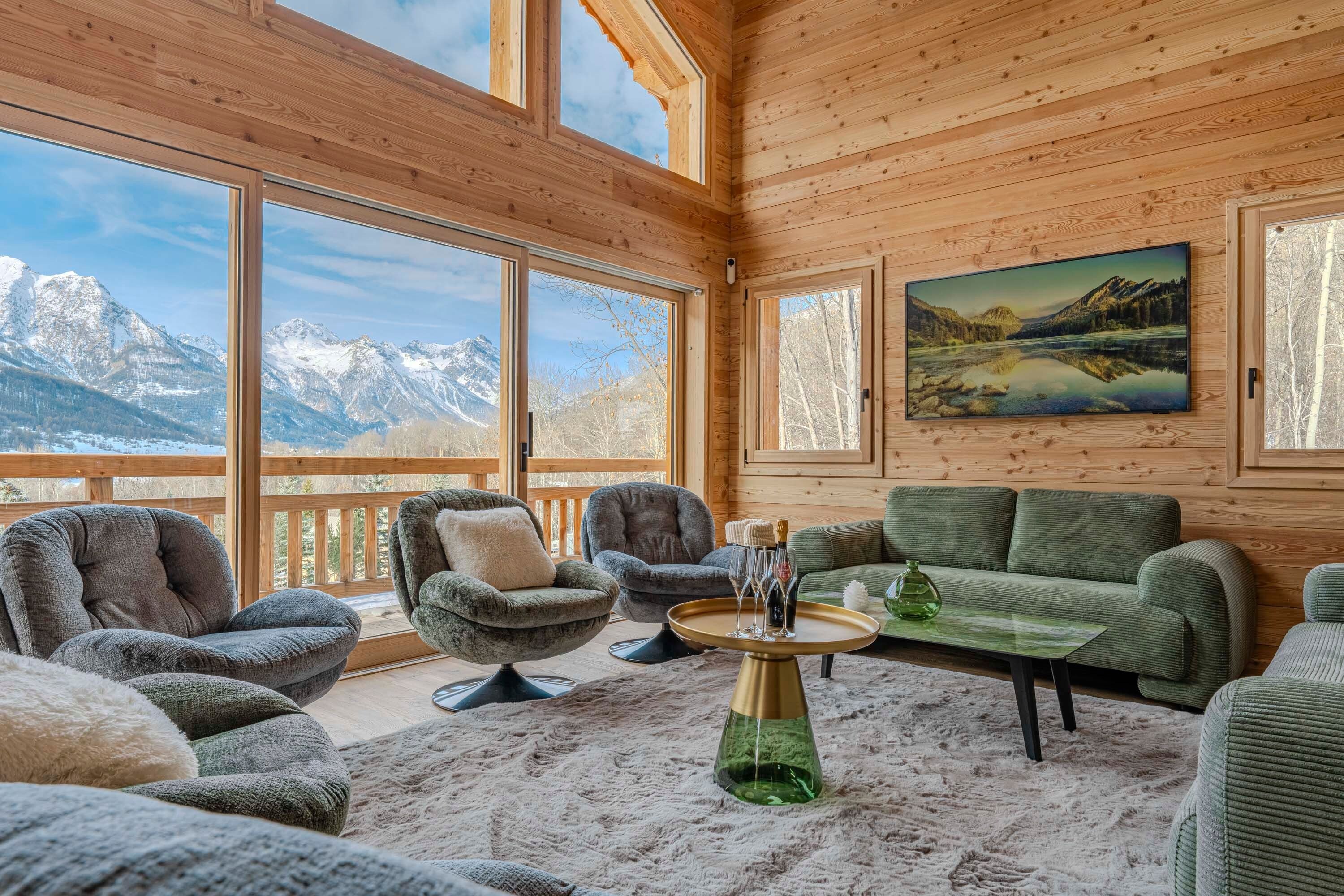 Ein Holzinnenraum mit Blick auf schneebedeckte Berge durch große Fenster.