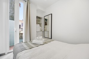 Ein Hotelzimmer mit Bett, Schrank, Spiegel und einem Balkon.