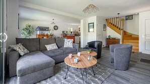 Ein modernes Wohnzimmer mit einer Eckcouch, einem runden Couchtisch und einer Treppe.