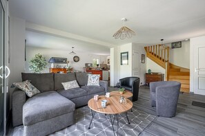 A modern living room with a sectional sofa, a round coffee table, and a staircase. - Ty Kerdreven - Maison familiale avec grand jardin (Crac'h)
