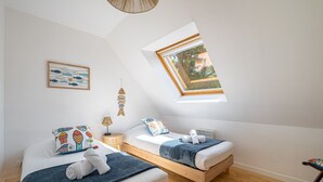 Ein Schlafzimmer mit zwei Betten, einem Oberlicht, einer Pendelleuchte und einem an der Wand hängenden Bild.