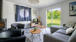Ein modernes Wohnzimmer mit Kamin, Sofa, Couchtisch und Blick ins Freie.
