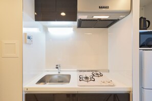 Una cocina con encimera blanca, pileta de acero inoxidable, estufa a gas y horno empotrado.