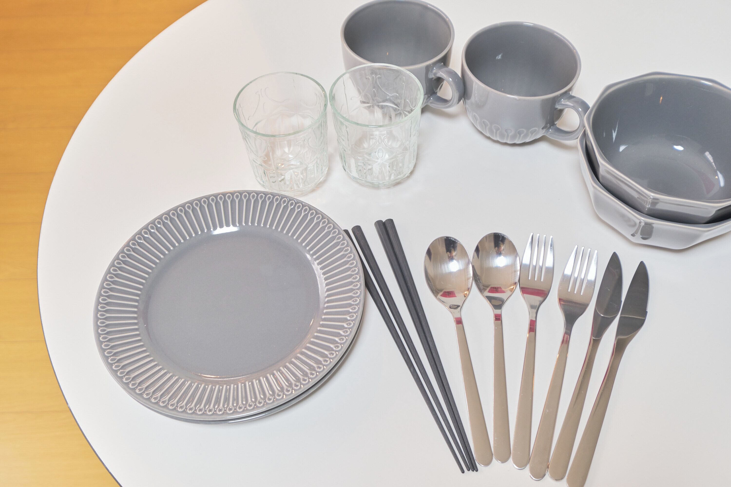 Uma mesa posta com prato, talheres, copos e uma tigela.