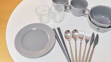 Uma mesa posta com prato, talheres, copos e uma tigela.