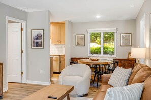 Uma sala de estar moderna com sofá, poltrona e mesa de jantar.