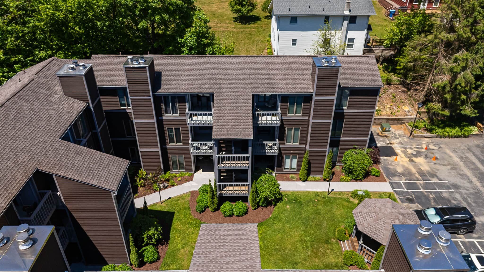 A multi-story building with a central courtyard, balconies, and a parking area.