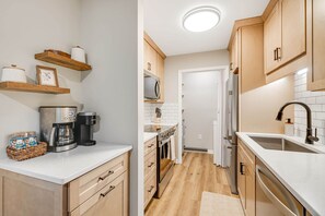 A modern kitchen with wooden cabinets, a microwave, a refrigerator, and a coffee maker. - Newly Renovated 1st Floor Condo | Walk to Main St. (Blowing Rock)