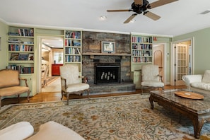 A living room with a fireplace, bookshelves, and a ceiling fan. - Historic BR Home | Walk to Main St | Pet Friendly (Blowing Rock)