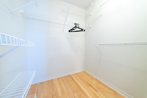Um quarto com piso de madeira, paredes brancas e estantes de metal.