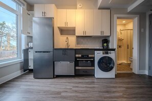 Cocina compacta con refrigerador, horno, microondas y lavadora.