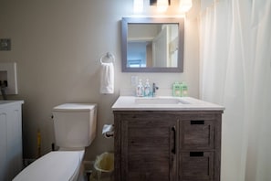 Ein Badezimmer mit Toilette, Waschbecken, Spiegel und Mülleimer.
