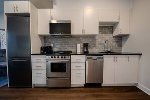 A modern kitchen with stainless steel appliances, white cabinetry, and a tiled backsplash. - Spacious Apartment near University of Ottawa (Ottawa)