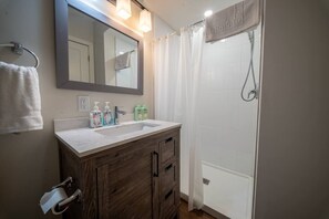 Une salle de bain équipée d’un lavabo, d’un miroir, d’un porte-serviettes et d’un rideau de douche.
