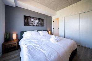 Ein Hotelzimmer mit einem großen Bett, einem Nachttisch mit Lampe, einem Wandbild und einer Tür.