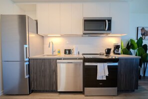 Eine moderne Küche mit einem Edelstahl-Kühlschrank, einer Mikrowelle, einem Geschirrspüler und einem Backofen.