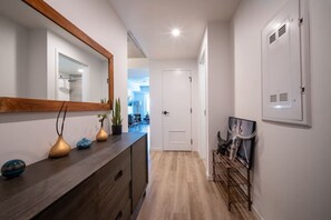 Ein Korridor mit Holzboden, einem dunklen Holzschrank mit Dekorationen, einem Spiegel und einer Tür zu einem anderen Raum.