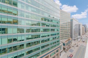 A modern multi-story building with large windows, a flat facade, and a parking area with cars.