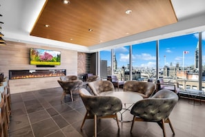 A modern conference room with a city view, a flat-screen TV, and a fireplace.