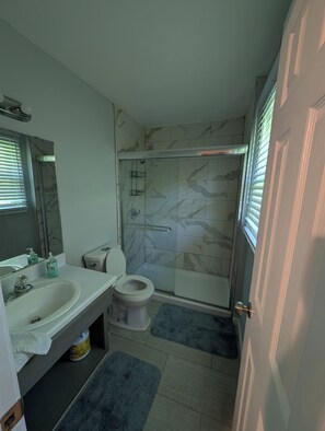 A bathroom with a shower, toilet, and sink. - Bring the crew to this comfortable 3/2 home minutes from everything in Anniston (Anniston)