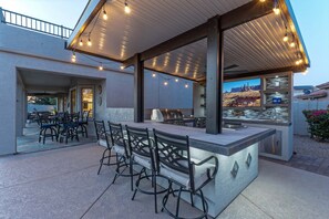 Ein Außenbereich mit Bar, Sitzgelegenheiten und Grill.