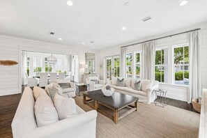 A spacious living room with a large sofa, a coffee table, and a dining area with chairs.
