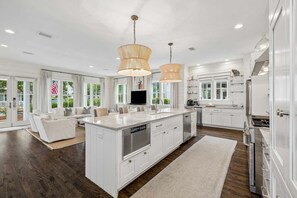 A modern kitchen with white cabinetry, a central island, stainless steel appliances, and pendant lighting.
