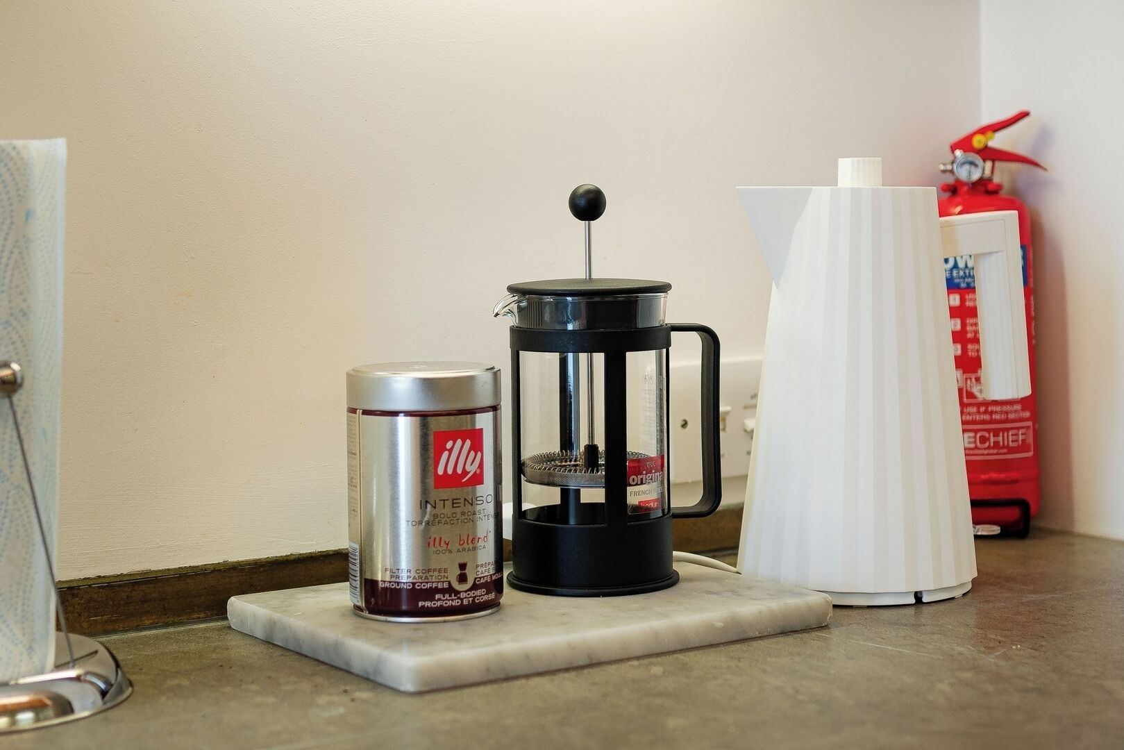 Eine Kaffeemaschine, eine Kaffeeverpackung und ein Feuerlöscher auf einer Küchenarbeitsplatte.
