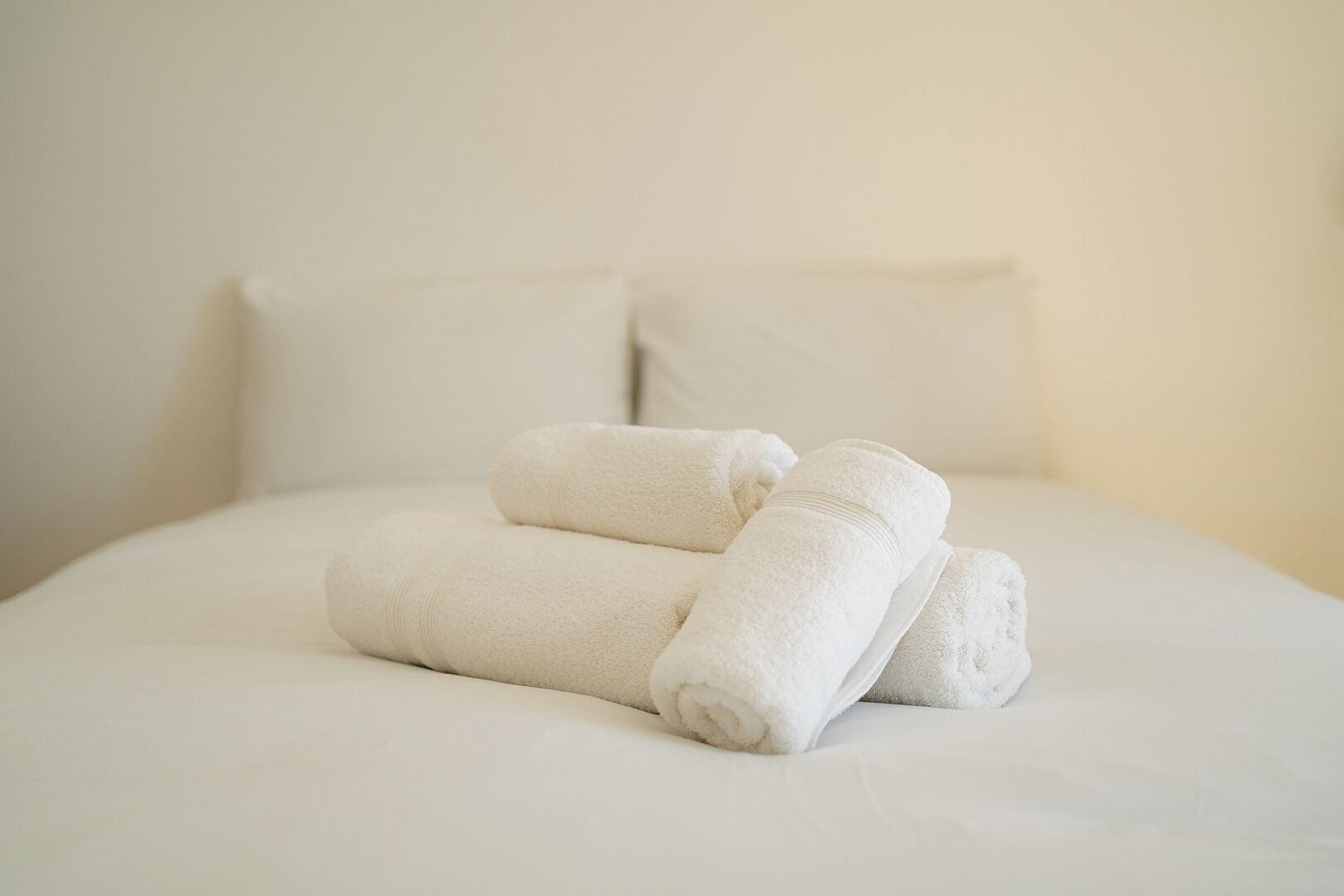 A neatly made bed with folded white towels and a pillow.
