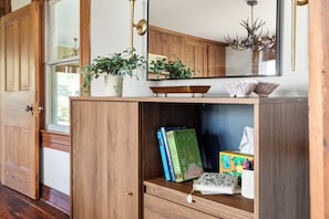 Ein Holzschrank mit Büchern, einer Pflanze und einem Spiegel.