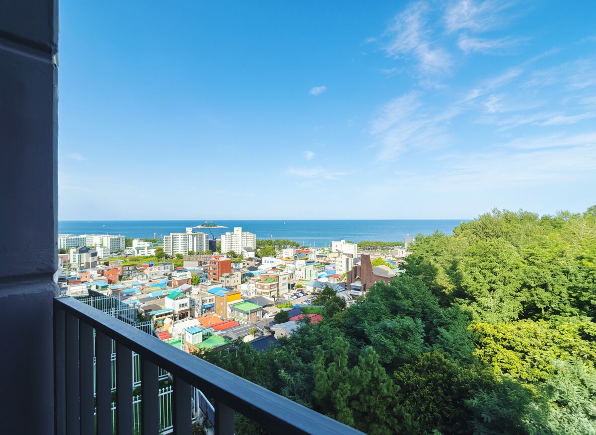 A cityscape with buildings, a clear sky, and a view of the sea.