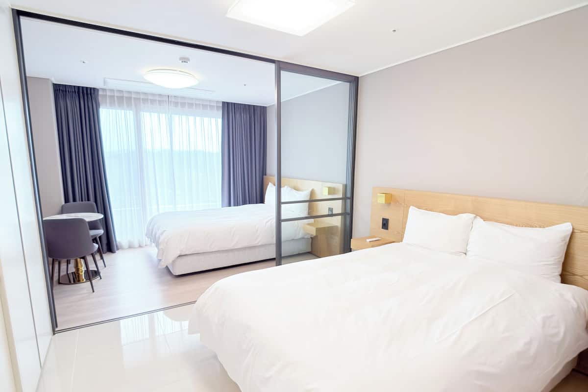 Una habitación de hotel moderna con una cama grande, un escritorio y un separador de vidrio.