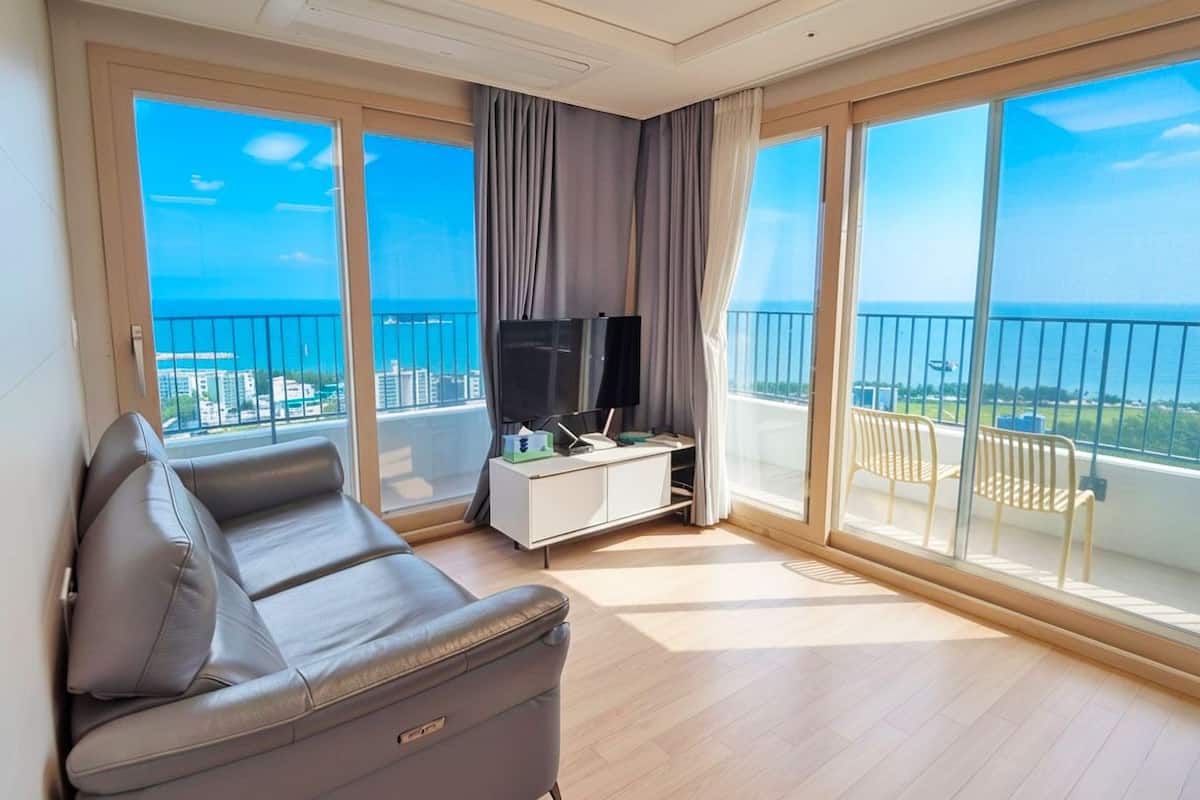 Una sala de estar moderna con un sofá, televisión y un balcón con vistas a la ciudad.
