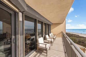 Ein Balkon mit Stühlen und einem Tisch, mit Blick auf einen Strand.