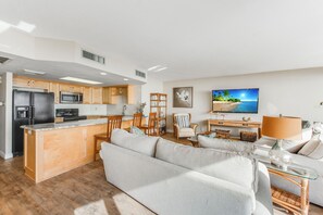Eine moderne Küche mit Kochinsel, Holzschränken und einem Essbereich mit Sofa und Lampe.