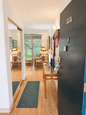 A room with a large mirror, a dark door with the number 375, wooden furniture, and a view through a glass door. - Soothing condo in Kihei perfect for relaxing stays (Kihei)